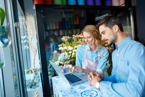 Florista y cliente con portátil - foto de stock