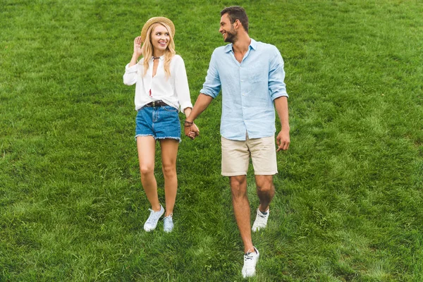 Pareja caminando sobre césped verde - foto de stock