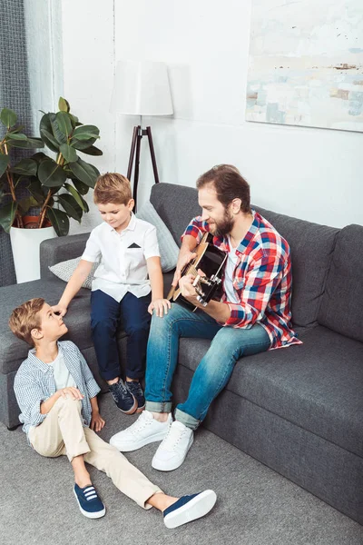 Отец с сыновьями, играющими на гитаре — стоковое фото