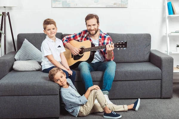 Отец с сыновьями, играющими на гитаре — стоковое фото