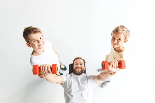 Padre e hijos haciendo ejercicio con pesas - foto de stock