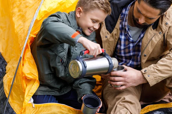 Filho com garrafa térmica no acampamento — Fotografia de Stock