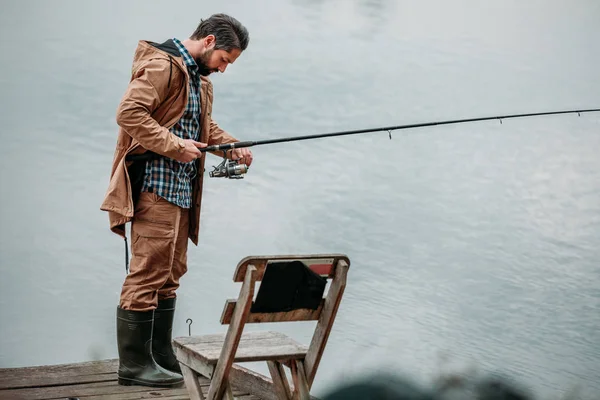 Людина риболовля зі стрижнем на пірсі — стокове фото