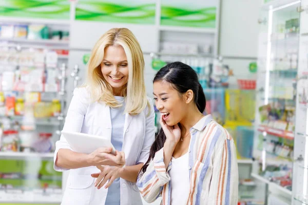 Pharmacist with digital tablet and customer — Stock Photo