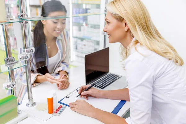 Farmacéutico y cliente en farmacia - foto de stock