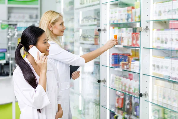 Farmacéuticos con dispositivos en farmacia - foto de stock