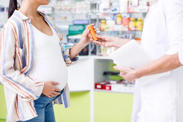 Farmacéutico dando pastillas a la mujer embarazada - foto de stock