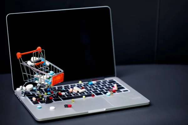 Laptop and pills in small shopping trolley — Stock Photo