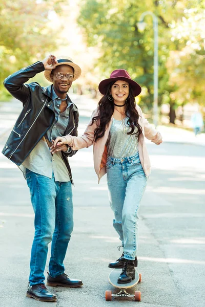 Fidanzato aiutare fidanzata skate su longboard — Foto stock