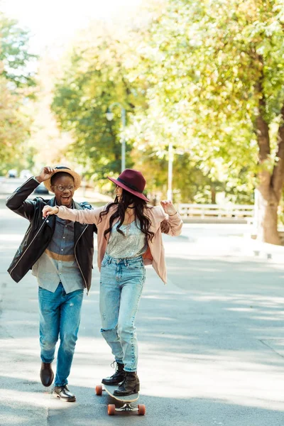 Novio ayudando a su novia a patinar en longboard - foto de stock