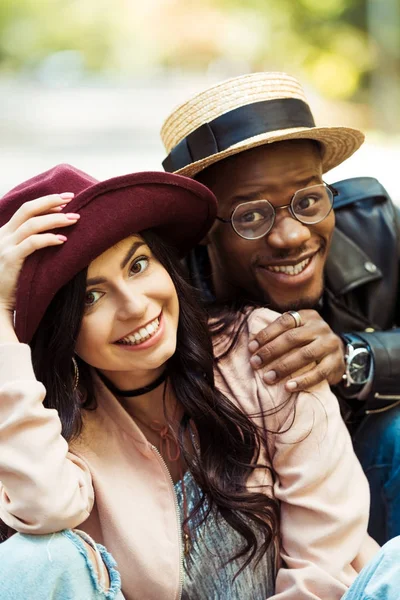 Sonriente pareja multicultural en sombreros - foto de stock
