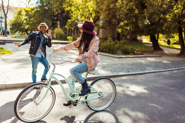 Girlfriend riding bike and boyfriend grimacing — Stock Photo