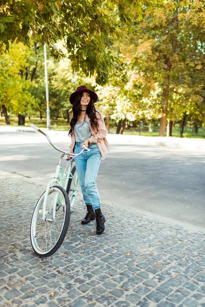 Mulher de chapéu de pé com bicicleta — Fotografia de Stock