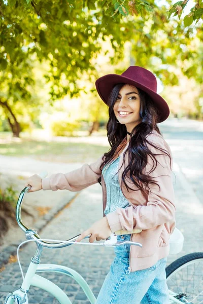 Donna in cappello in piedi con bicicletta — Foto stock