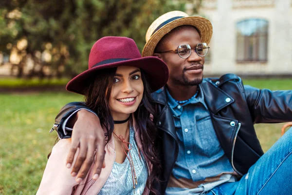 Multicultural couple sitting on grass — Stock Photo