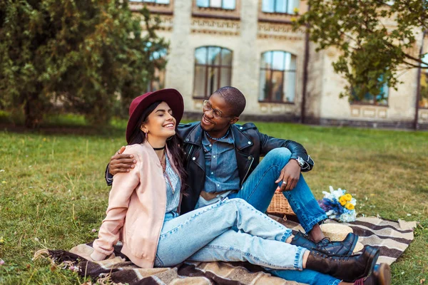 Pareja multicultural sentada en manta - foto de stock