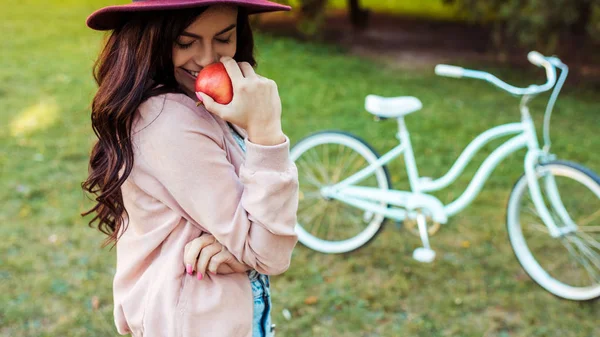 Femme au chapeau tenant pomme rouge — Photo de stock