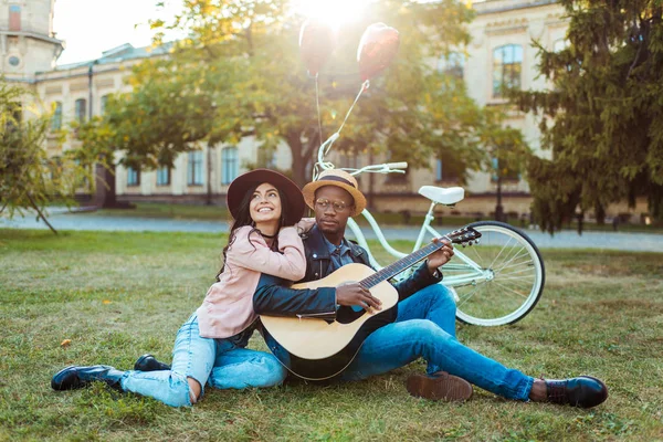 Couple assis avec guitare dans le parc — Photo de stock