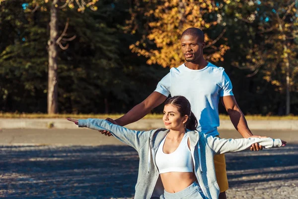 Petit ami aider petite amie étirement — Photo de stock