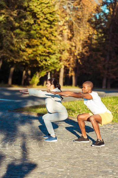 Couple squatting in park — Stock Photo
