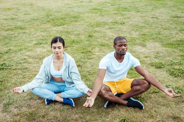 Interracial couple sitting in Lotus Position — Stock Photo
