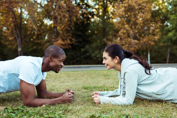 Pareja haciendo ejercicio tablón sobre hierba - foto de stock