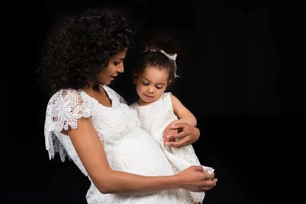 Daughter looking at pregnant mothers belly — Stock Photo