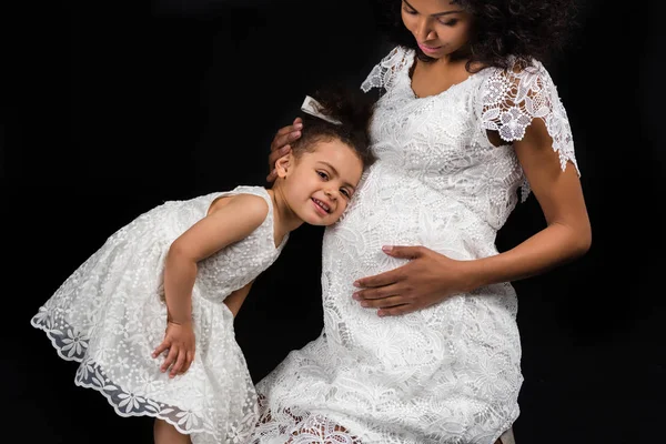 Дочь слушает беременных матерей живот — стоковое фото
