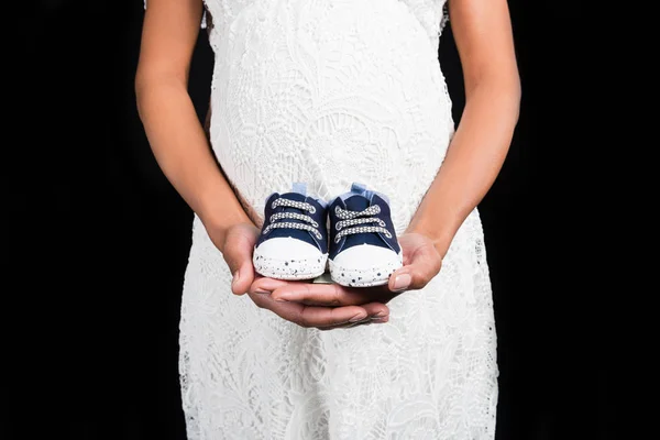 Pregnant woman holding small shoes — Stock Photo