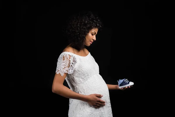 Pregnant woman holding small shoes — Stock Photo