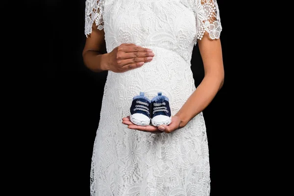 Donna incinta che tiene piccole scarpe — Foto stock
