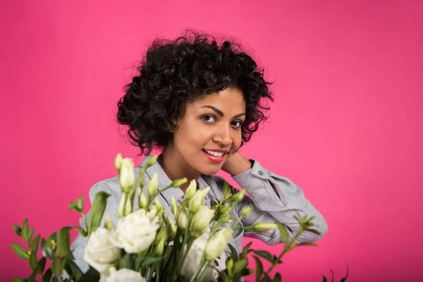 Frau lächelt und steht mit Blumen — Stockfoto