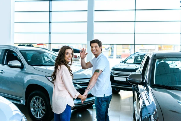 Hombre saludando mano en sala de exposición de coches - foto de stock