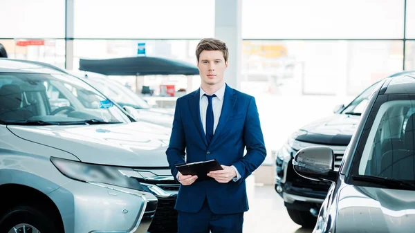 Gerente de pé entre carros no showroom — Fotografia de Stock