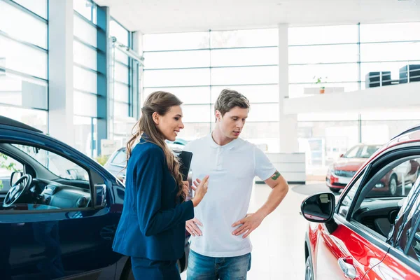 Sales manager describing car to customer — Stock Photo