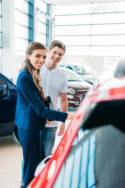 Directeur des ventes montrant la voiture au client — Photo de stock