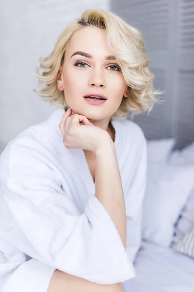 Portrait of beautiful young blonde woman in bathrobe looking at camera — Stock Photo