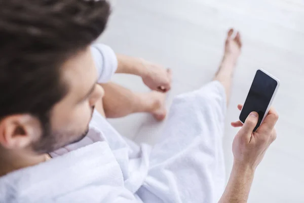 Foyer sélectif de l'homme barbu en peignoir à l'aide d'un smartphone avec écran blanc — Photo de stock