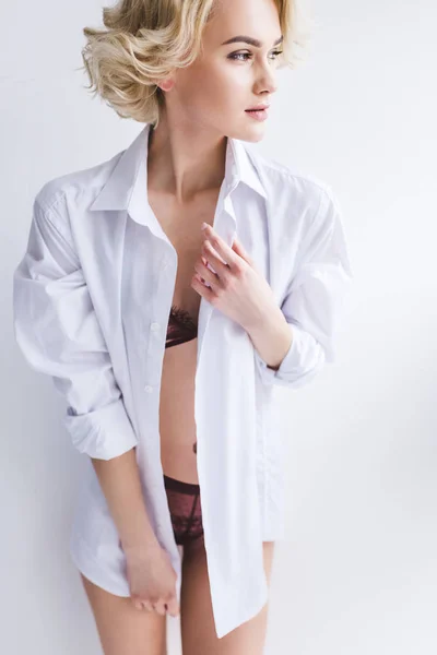 Beautiful blonde woman in underwear and shirt looking away on white — Stock Photo