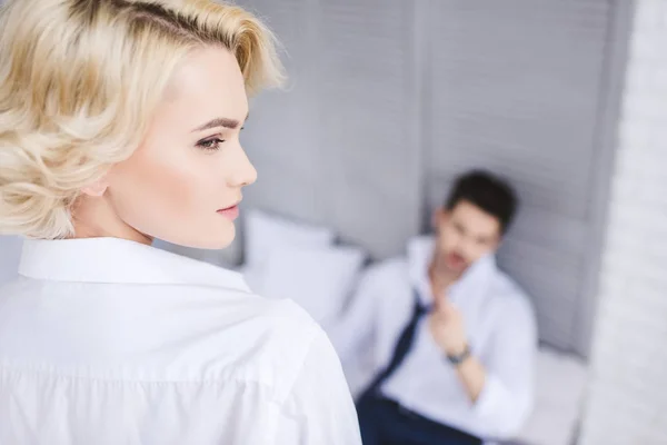 Belle fille blonde regardant loin tandis que petit ami couché sur le lit — Photo de stock