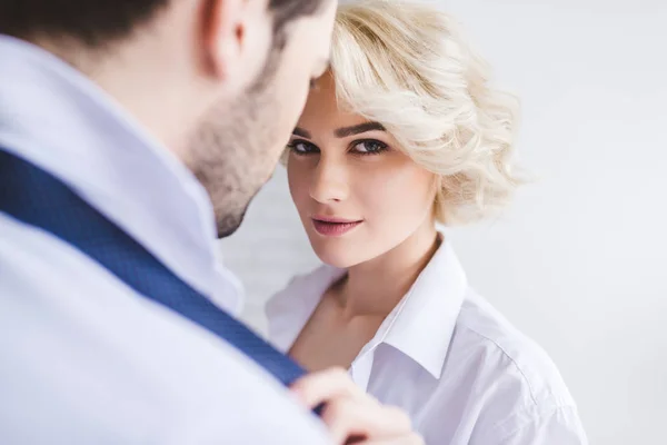 Junge Frau schaut in die Kamera, während sie die Krawatte ihres Freundes auszieht — Stockfoto