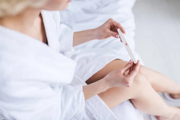 Cropped shot of young woman in bathrobe holding positive pregnancy test — Stock Photo