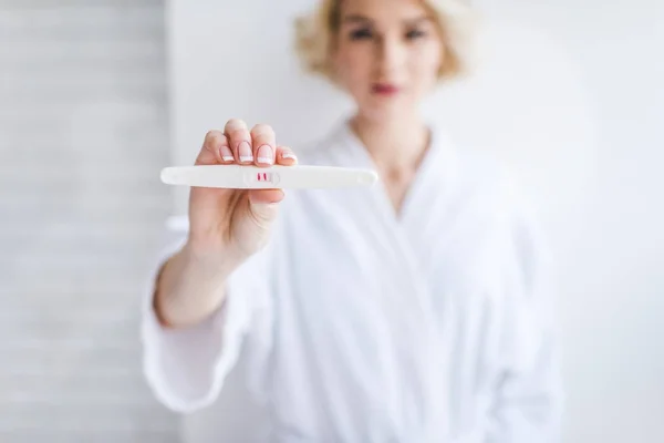 Vista de cerca de una mujer joven que tiene una prueba de embarazo positiva - foto de stock