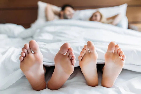 Petit ami et petite amie couché au lit avec les pieds au premier plan — Photo de stock