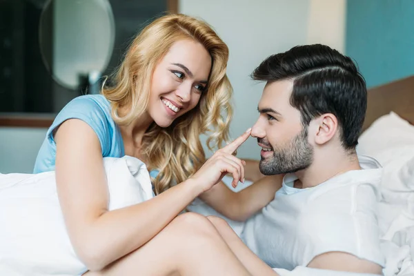 Fidanzata sorridente toccare il naso fidanzato a letto — Foto stock