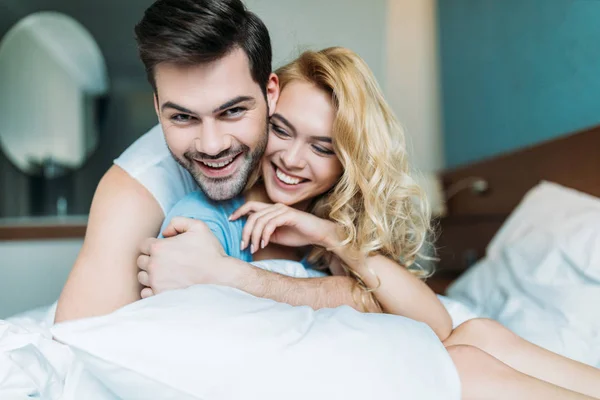Lächelnd heterosexuelles Paar, das sich auf dem Bett umarmt — Stockfoto