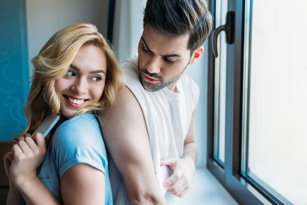 Sonriente pareja ocultar los teléfonos inteligentes el uno del otro - foto de stock