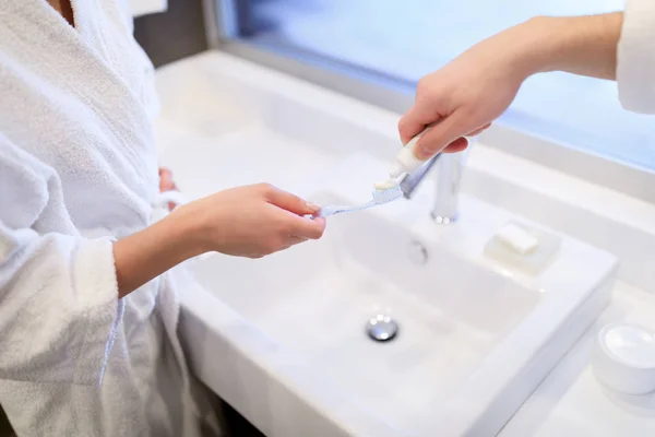 Imagen recortada de novio aplicando pasta de dientes en cepillo de dientes novia en el baño - foto de stock