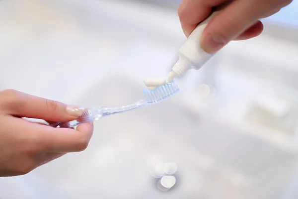 Обрезанное изображение парня, наносящего зубную пасту на зубную щетку подруги — стоковое фото