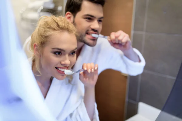 Coppia affettuosa lavarsi i denti e guardando lo specchio — Foto stock